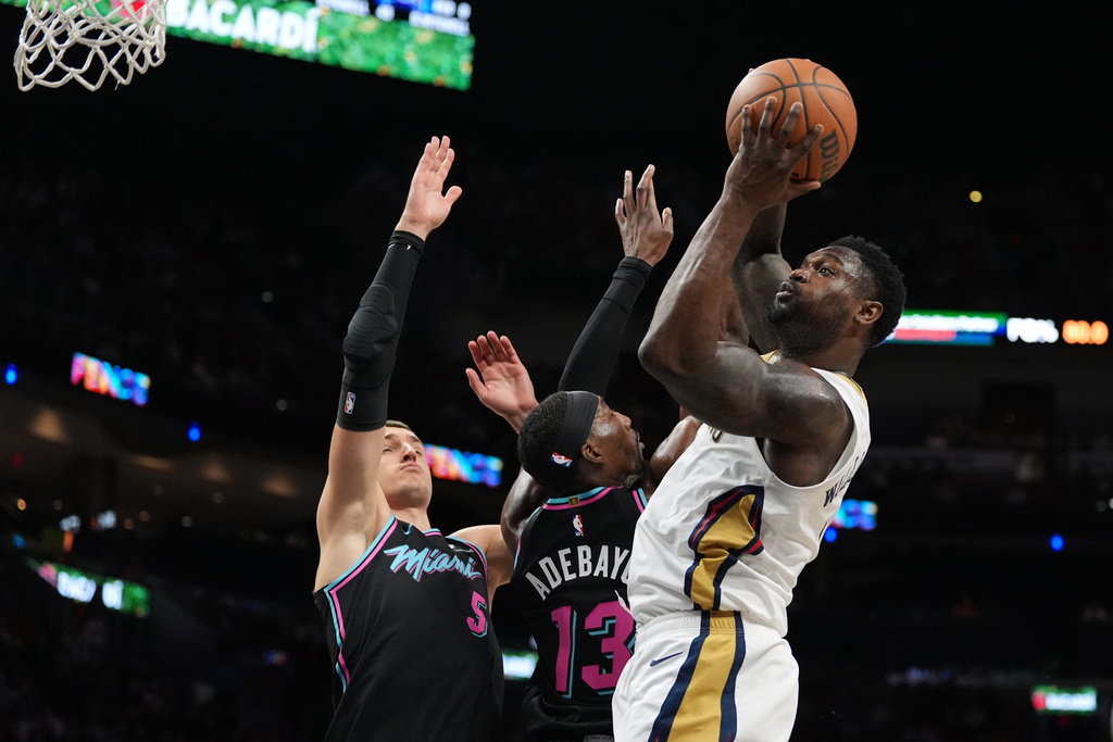 New Orleans Pelicans forward Zion Williamson shoots over Miami Heat forward Nikola Jovic (5) and center/forward Bam Adebayo (13) during the first half of an NBA basketball game, Sunday, Jan. 4, 2026, in Miami. (AP Photo/Rebecca Blackwell)