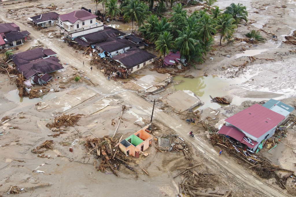 In this aerial photo taken using a drone, people are seen making their way on a muddy road at a village affected by a flash flood in Batang Toru, North Sumatra, Indonesia, Tuesday, Dec. 2, 2025. (AP Photo/Binsar Bakkara)