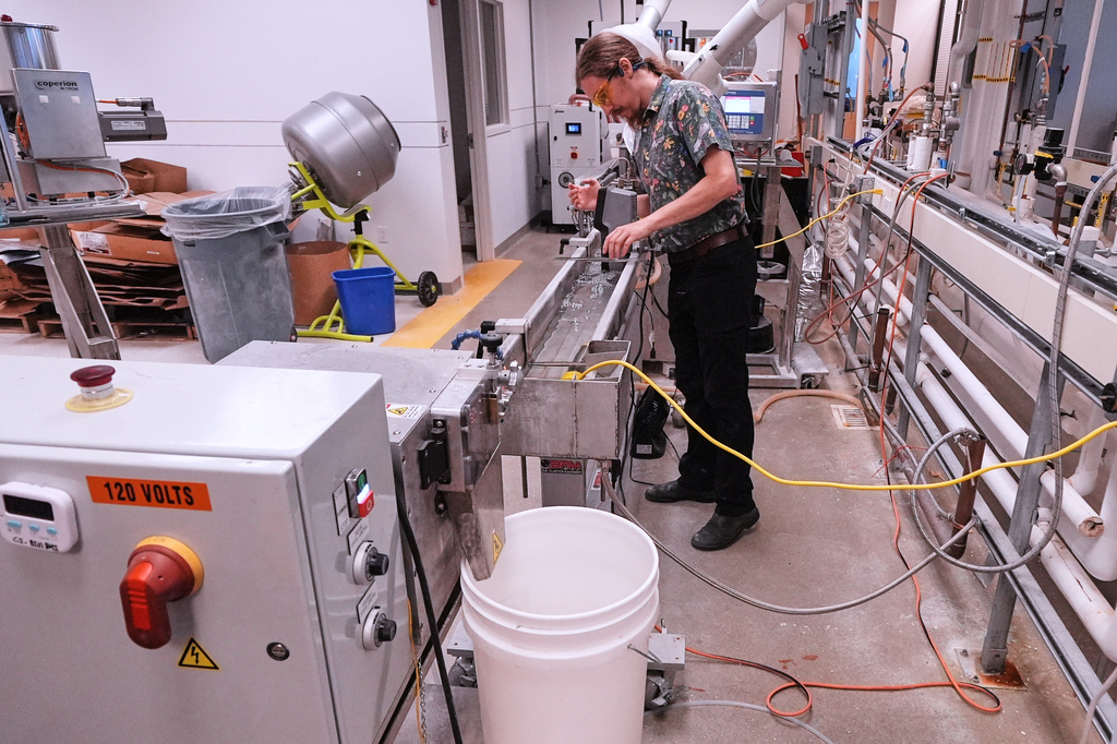Lab technician Fen Spinney calibrates a machine that is used in compounding bioplastic pellets at CJ Biomaterials, Monday, Aug. 3, 2026, in Woburn, Mass. (AP Photo/Charles Krupa)
