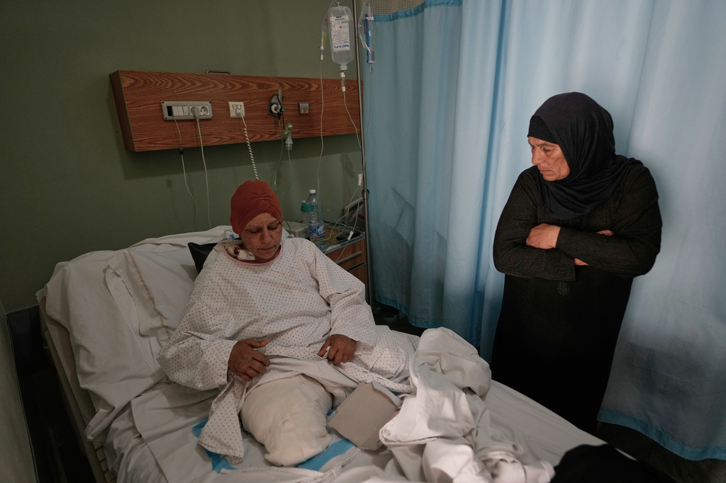 Sanaa Khalil, 35, a Syrian farmer who lost her two legs in the past days by an Israeli airstrike while she was working at a banana plantation, lies on a bed as she is assisted by a relative at a hospital in the southern port city of Tyre, Lebanon, Friday, May 1, 2026. (AP Photo/Hussein Malla)