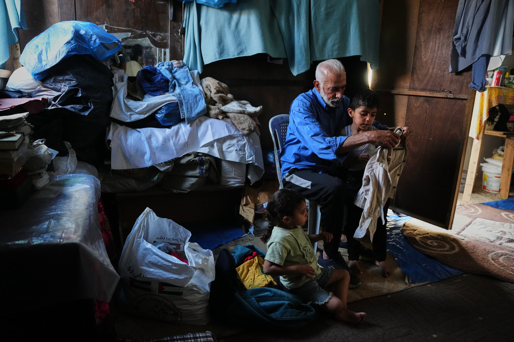 Mahmoud Nofal, 64, cares for his grandchildren, Tamim and Raneen Nofal, whom he has raised since their parents were killed in an Israeli airstrike, in Khan Younis, southern Gaza Strip, June 2, 2026. (AP Photo/Abdel Kareem Hana)