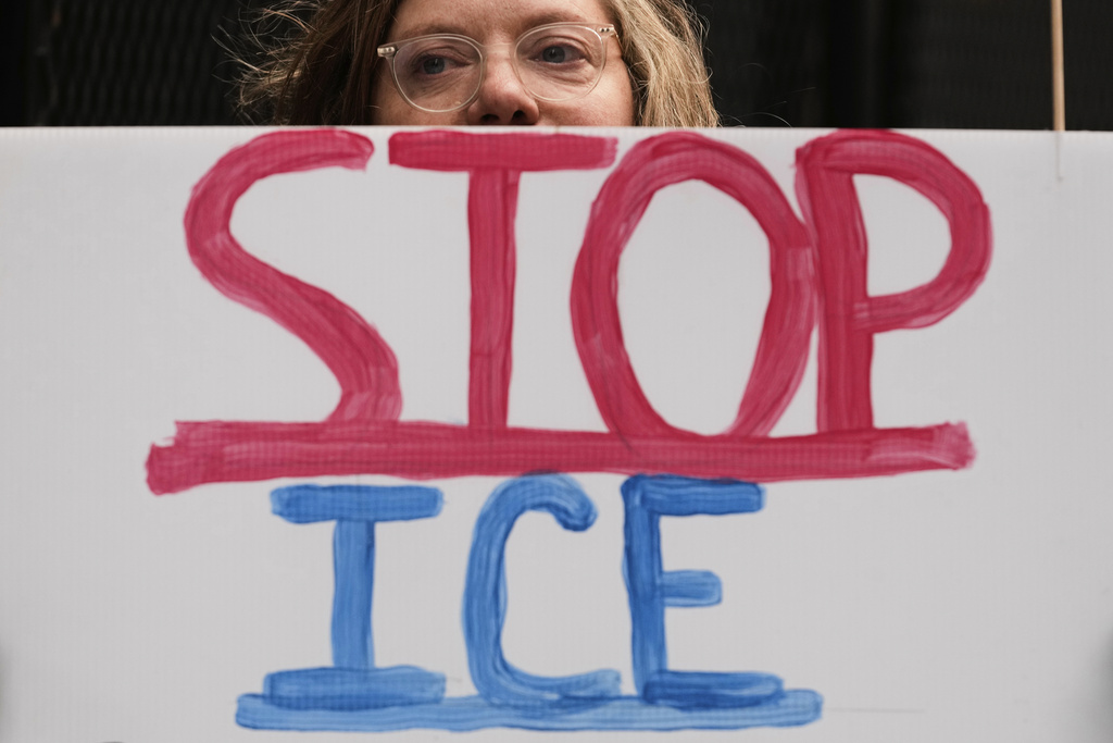 A woman holds a sign as she waits for U.S. Customs and Border Patrol Gregory Bovino outside federal court in Chicago, Tuesday, Oct. 28, 2025. (AP Photo/Nam Y. Huh)