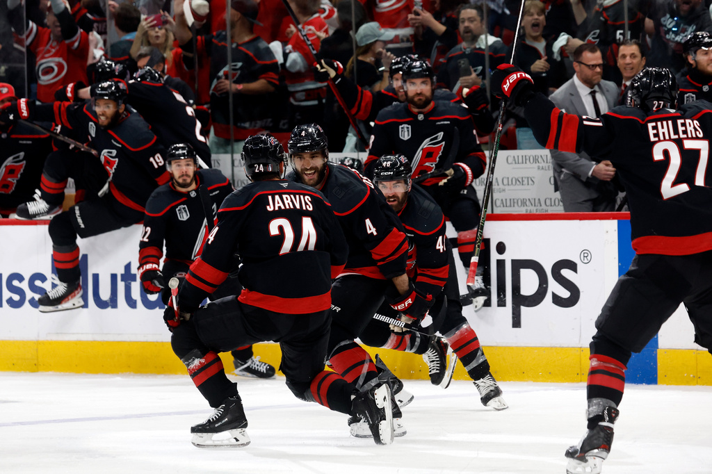 Carolina Hurricanes' Seth Jarvis (24) celebrates after his winning goal with teammates Shayne Gostisbehere (4), and Jordan Martinook (48) with Nikolaj Ehlers (27) nearby following the overtime period in Game 2 of the NHL hockey Stanley Cup Final series against the Vegas Golden Knights in Raleigh, N.C., Thursday, June 4, 2026. (AP Photo/Karl DeBlaker)