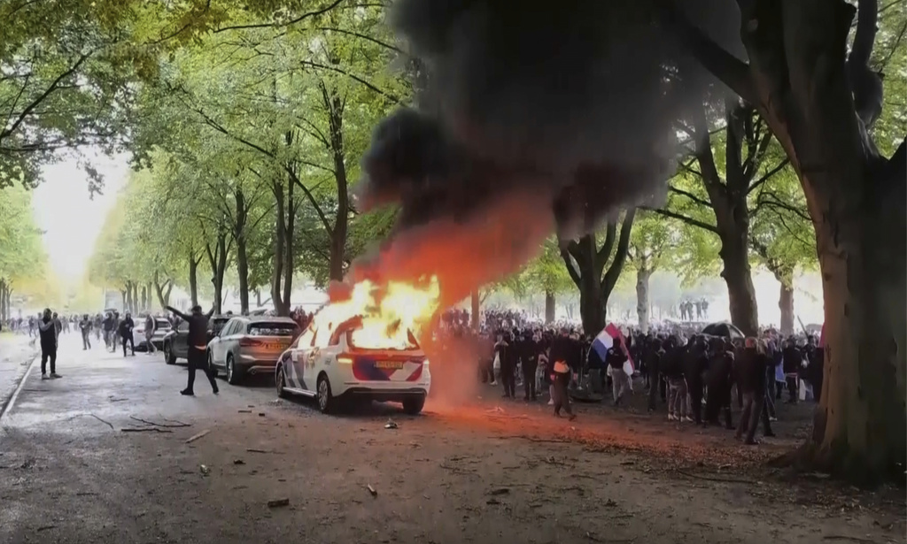A police vehicle burns as a right-wing demonstration erupted into violence and chaos as rioters clashed with police on Saturday, Sept. 20, 2025 in The Hague, Netherlands. (REGIO8 via AP)