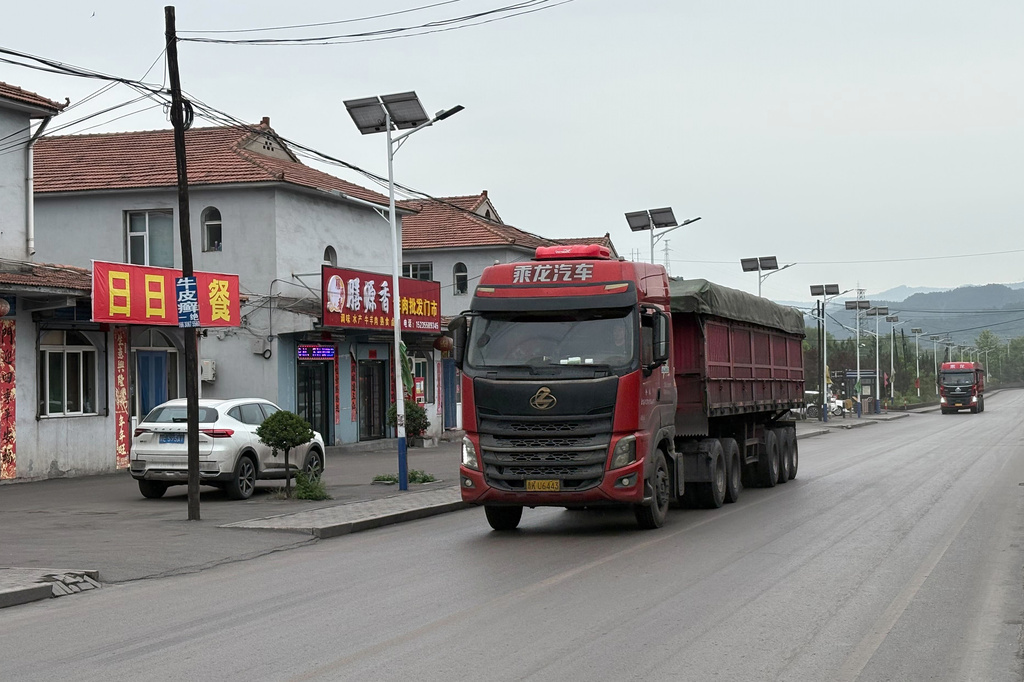 Trucks move past Shangzhuang village where some miners are lived and worked at the Liushenyu coal mine facility in Qinyuan county in Changzhi, northern China's Shanxi province on Sunday, May 24, 2026. (AP Photo/E. Eduardo Castillo)