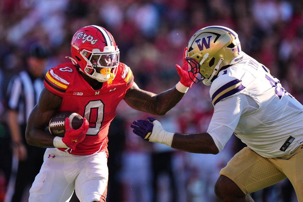 Maryland running back Dejuan Williams (0) runs against Washington defensive lineman Deshawn Lynch, right, during the first half of an NCAA college football game, Saturday, Oct. 4, 2025, in College Park, Md. (AP Photo/Stephanie Scarbrough)