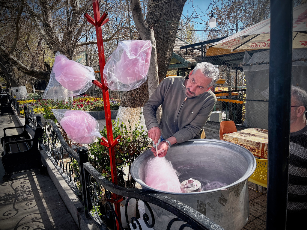 A man spins cotton candy for passersby in a public park near Road 2 in Tabriz, Iran, Thursday, April 9, 2026. (AP Photo/Francisco Seco)