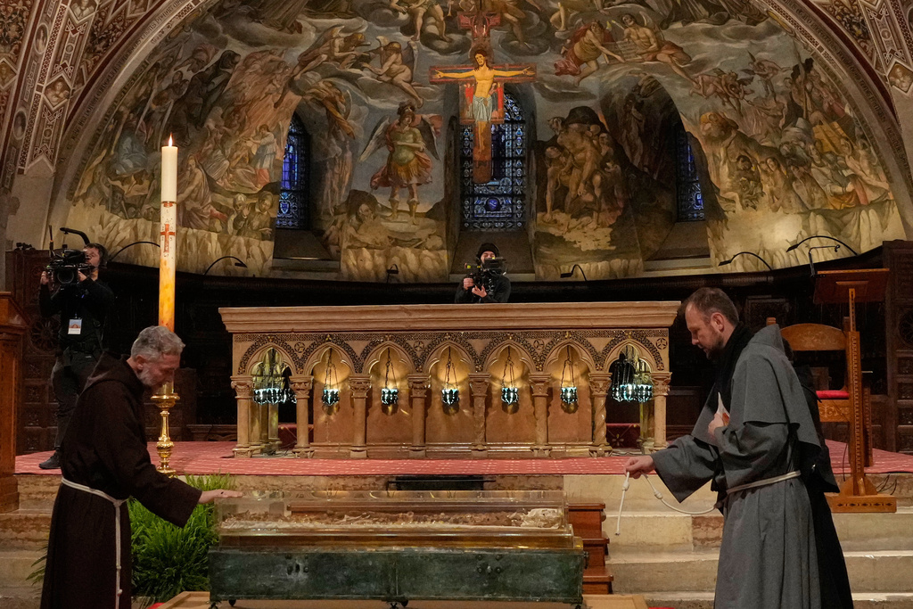 Friars pray before the remains of Francis of Assisi inside the Basilica of St. Francis of Assisi in Assisi, Italy, Saturday, Feb. 21, 2026, on the eve of a public exposition beginning Feb. 22 to mark the 800th anniversary of his death in 1226. (AP Photo/Gregorio Borgia)