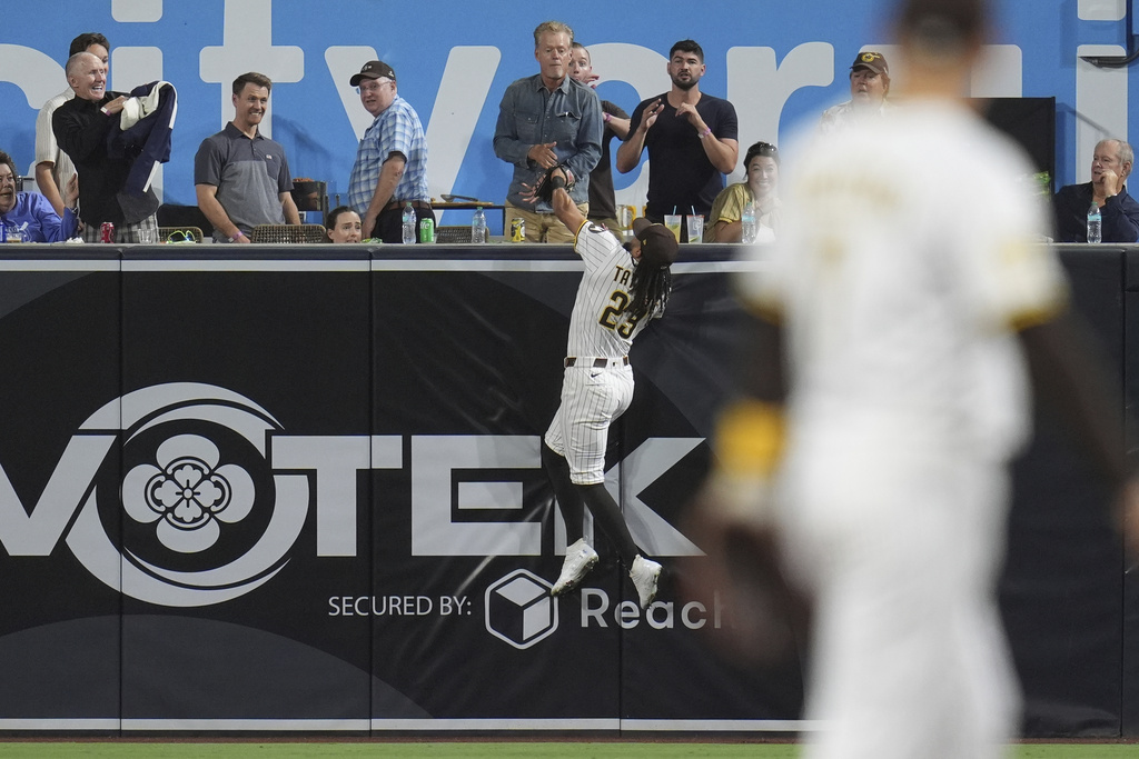 San Diego Padres right fielder Fernando Tatis Jr. makes a catch over the wall for the out on Cincinnati Reds' Tyler Stephenson during the fourth inning of a baseball game Tuesday, Sept. 9, 2025, in San Diego. (AP Photo/Gregory Bull)