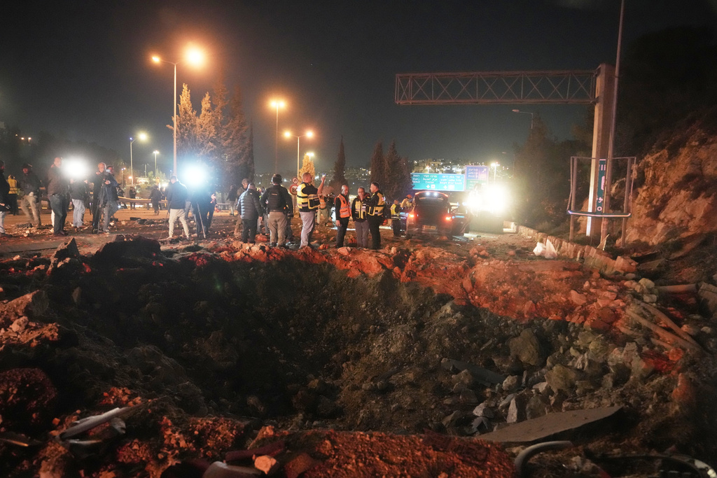 Israeli security forces inspect a damaged road after a missile launched from Iran struck Jerusalem, Sunday, March 1, 2026.(AP Photo/Mahmoud Illean)