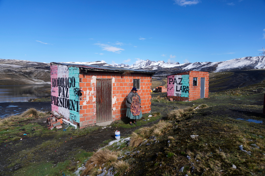FILE - A woman stands next to a mural promoting presidential candidate Rodrigo Paz ahead of the presidential runoff election, on the outskirts of La Paz, Bolivia, Oct. 18, 2025. (AP Photo/Juan Karita, File)
