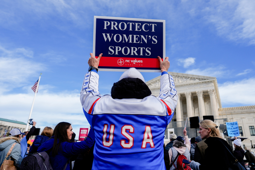 A protester holds a sign outside the Supreme Court during arguments over state laws barring transgender girls and women from playing on school athletic teams, Tuesday, Jan. 13, 2026, in Washington. (AP Photo/Julia Demaree Nikhinson)