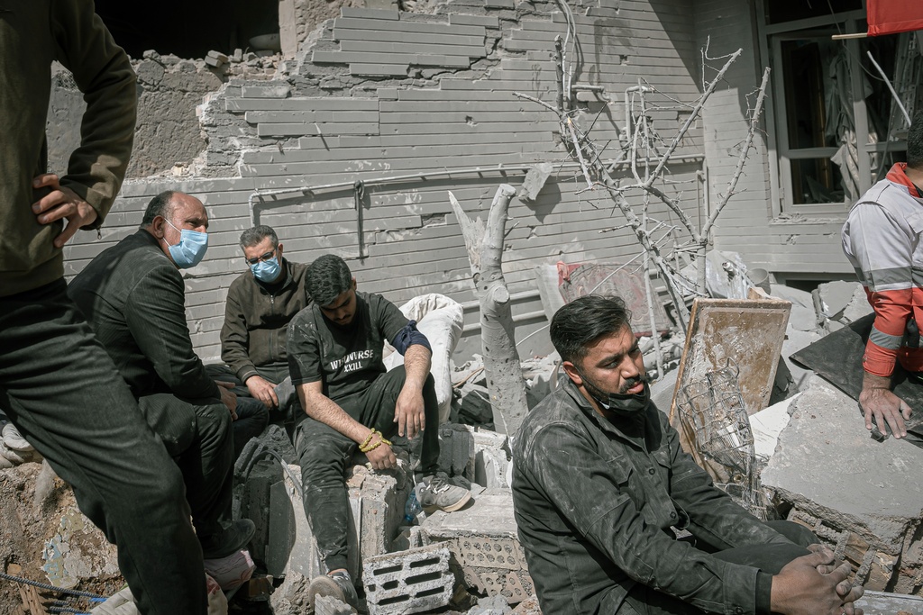 Volunteers rest as first responders inspect the rubble and search for victims at a residential building hit in an overnight strike during the U.S.-Israeli military campaign in Tabriz, East Azerbaijan Province, northwestern Iran, Tuesday, March 24, 2026. (AP Photo/Matin Hashemi)