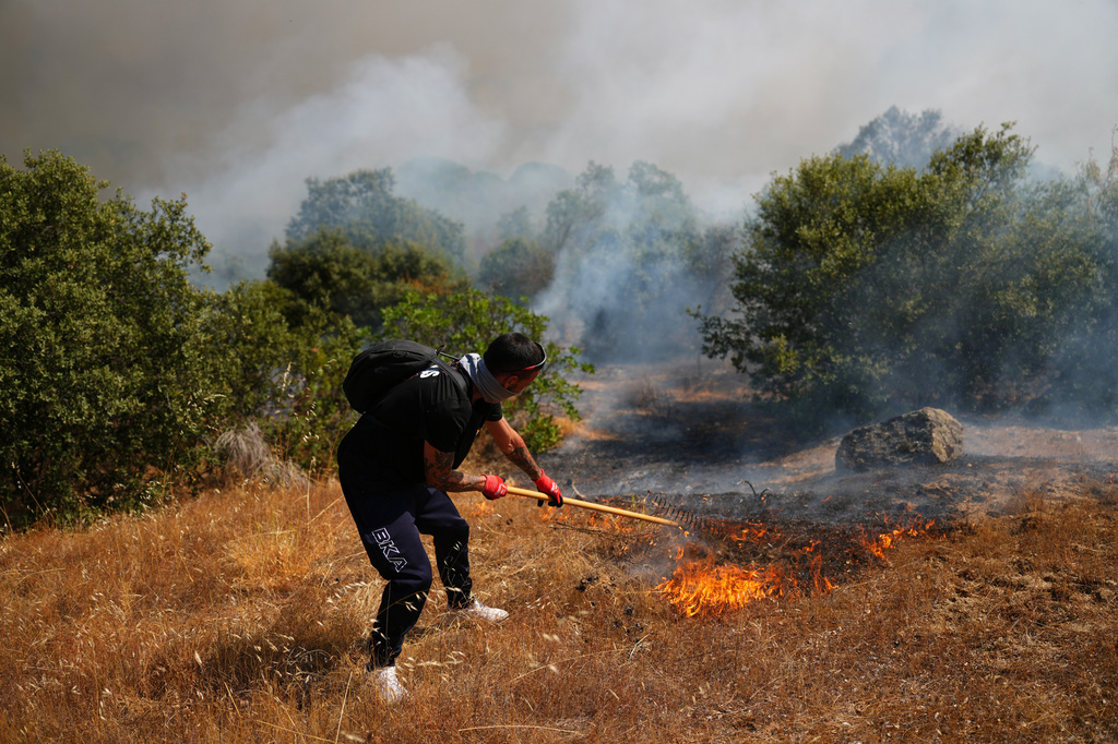 FILE - A volunteer uses a rake trying to help stop a wildfire from advancing in San Martin de Valdeiglesias, west of Madrid, Spain, July 26, 2026. (AP Photo/Manu Fernandez, File)