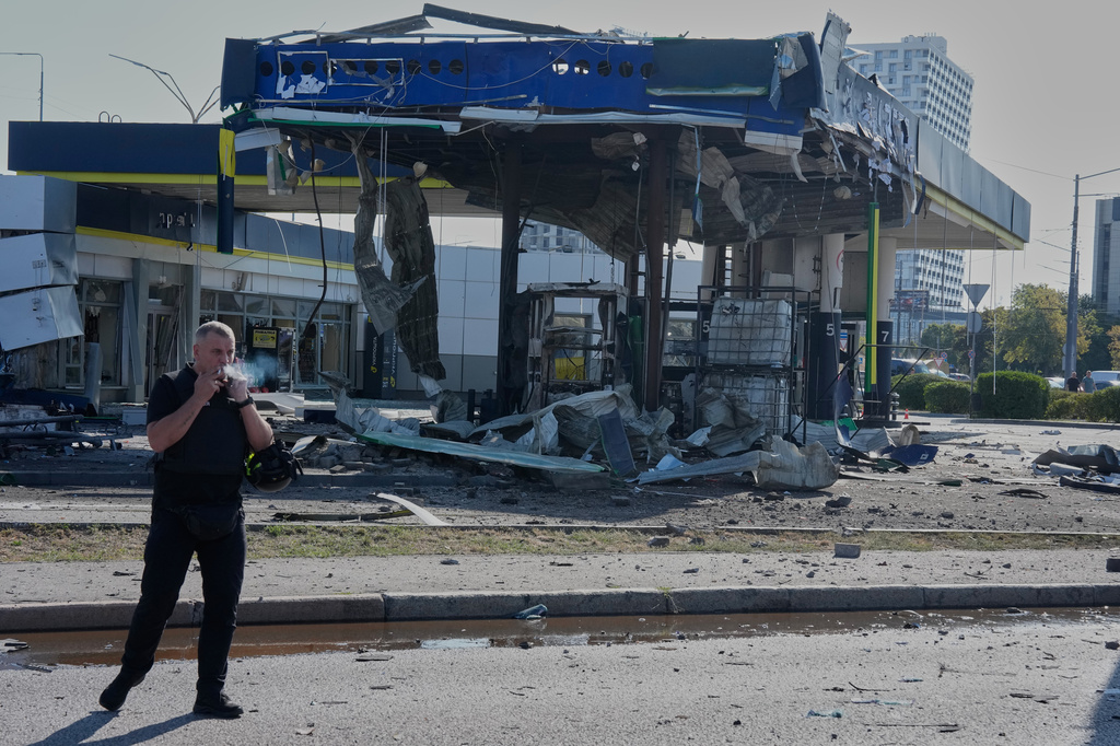 A policeman smokes near a damaged gas station after a Russian drone strike in Kyiv, Ukraine, Friday, Sept. 11, 2026. (AP Photo/Efrem Lukatsky)