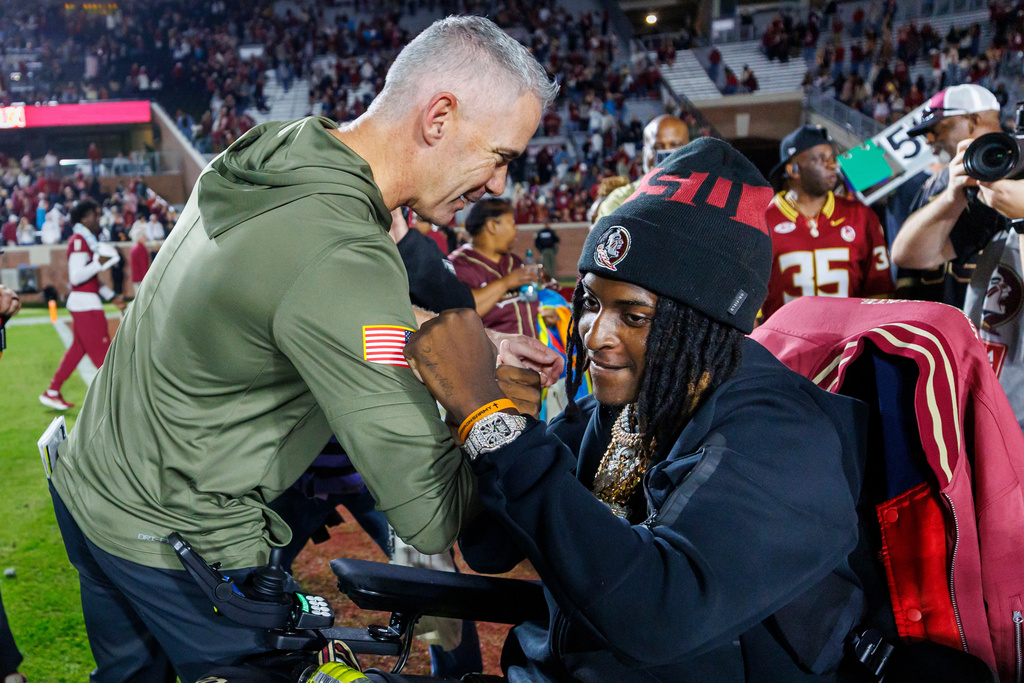 Florida State head coach Mike Norvell, left, celebrates with gunshot-wounded linebacker Ethan Pritchard, right, after an NCAA college football game against Virginia Tech, Saturday, Nov. 15, 2025, in Tallahassee, Fla. (AP Photo/Colin Hackley)