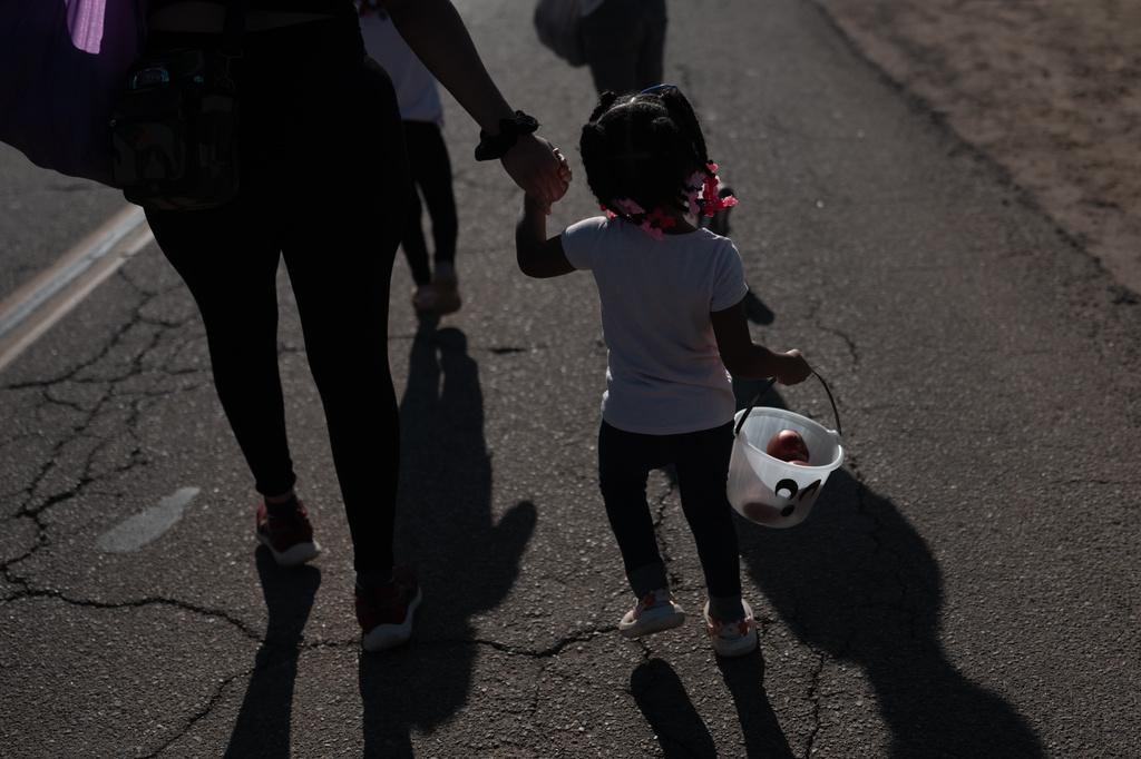 Elianna Ealey holds her mother's hand while carrying a small bucket with nectarines during a free giveaway at Cesar Mora's orchard in Reedley, Calif., Wednesday, July 1, 2026. (AP Photo/Jae C. Hong)