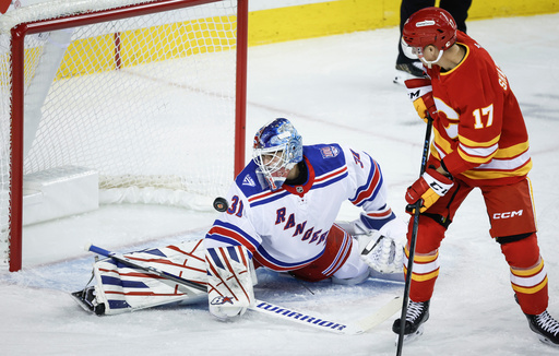 New York Rangers goalie Igor Shesterkin, left, deflects a shot by Calgary Flames' Yegor Sharangovich, right, during first-period NHL hockey game action in Calgary, Alberta, Sunday, Oct. 26, 2025. (Jeff McIntosh/The Canadian Press via AP) New York Rangers goalie Igor Shesterkin, left, deflects a shot by Calgary Flames' Yegor Sharangovich, right, during first-period NHL hockey game action in Calgary, Alberta, Sunday, Oct. 26, 2025. (Jeff McIntosh/The Canadian Press via AP)