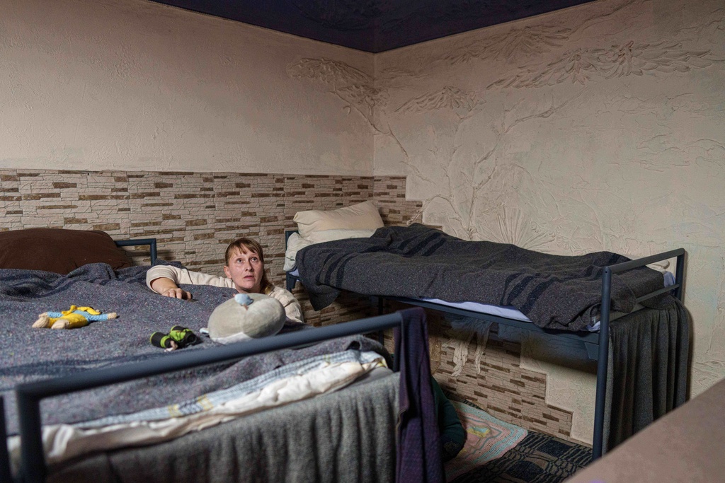 A woman makes her bed at the hostel for displaced persons in Dnipro, Ukraine, Wednesday, Oct. 8, 2025. (AP Photo/Evgeniy Maloletka)