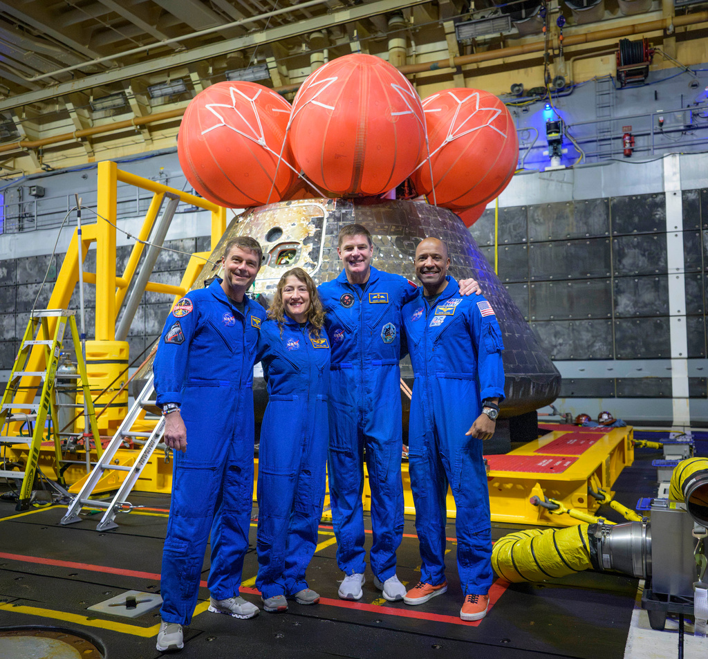 In this photo provided by NASA, from left, NASA astronauts Reid Wiseman, commander; Christina Koch, mission specialist; CSA (Canadian Space Agency) astronaut Jeremy Hansen, mission specialist; and NASA astronaut Victor Glover, Artemis II pilot, right, pose for a group photo after viewing the Orion spacecraft in the well deck of USS John P. Murtha, Saturday, April 11, 2026, in the Pacific Ocean off the coast of California. (Bill Ingalls/NASA via AP)