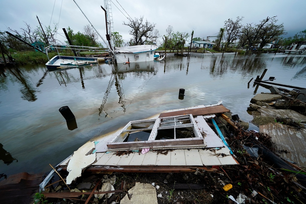 FILE - An oil sheen drifts between a sunken shrimp boat and pieces of a destroyed home along Bayou Pointe au Chien in the aftermath of Hurricane Ida in Pointe-aux-Chenes, La., Tuesday, Sept. 14, 2021. (AP Photo/Gerald Herbert, File)