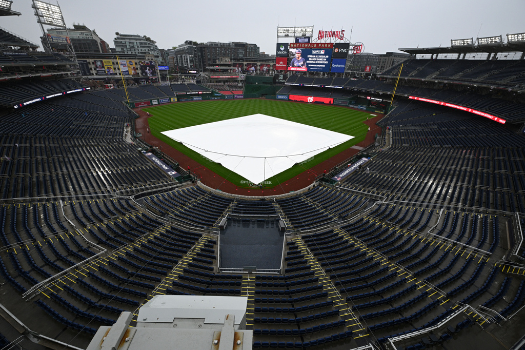 A tarp lies on the field as the baseball game between the Los Angeles Dodgers and Washington Nationals is being delayed due to inclement weather, Sunday, April 5, 2026, in Washington. (AP Photo/Nick Wass)