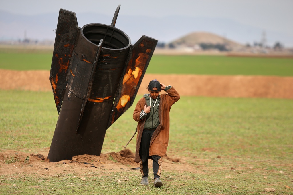 A shepherd boy walks away from an unexploded Iranian projectile that landed in an open field in the outskirts of Qamishli, eastern Syria, Wednesday, March 4, 2026.(AP Photo/Baderkhan Ahmad)