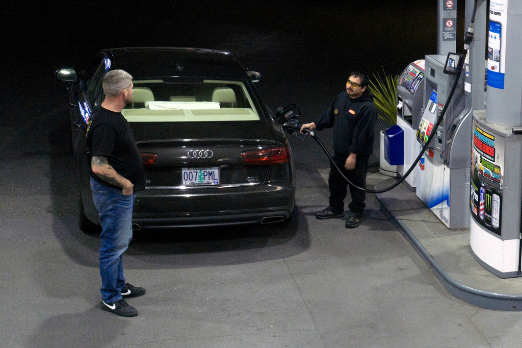 An attendant talks with a customer while fueling their tank at a gas station on Wednesday, May 6, 2026, in Portland, Ore. (AP Photo/Jenny Kane)