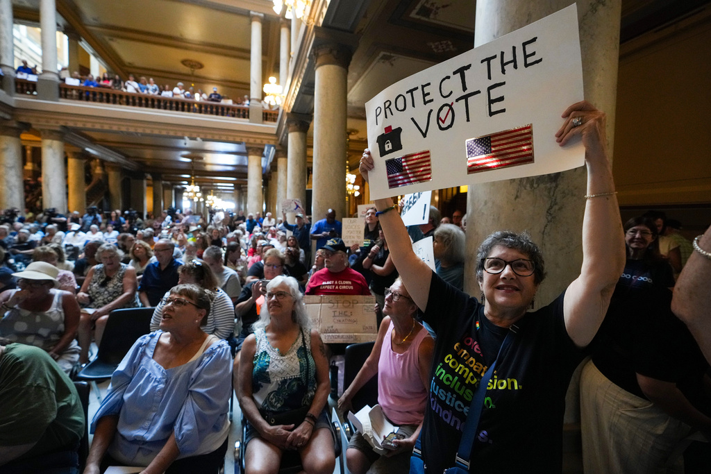 FILE - Annette Groos holds a sign before the start of a rally featuring former Transportation Secretary Pete Buttigieg at the Statehouse in Indianapolis, Thursday, Sept. 18, 2025 for Indiana Democrats amid pressure from President Donald Trump on Republicans who control the state's legislature to redistrict congressional seats. (AP Photo/Michael Conroy, File)