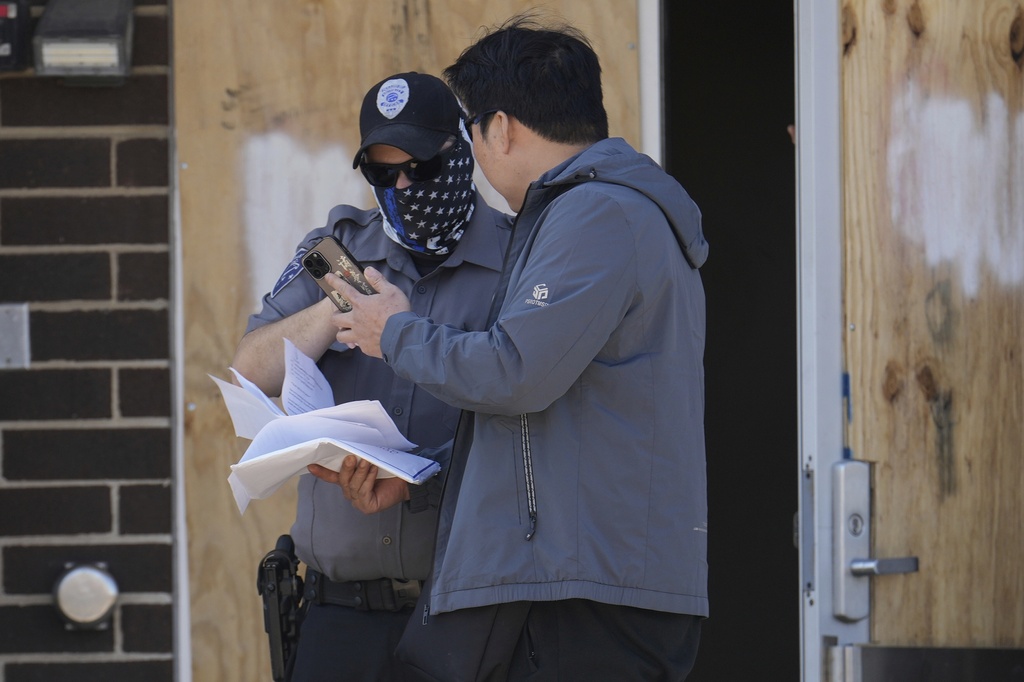 A person talks to a masked guard at the entrance of an immigration processing center Monday, Sept. 8, 2025, in Broadview, Ill., a suburb of Chicago. (AP Photo/Carolyn Kaster)