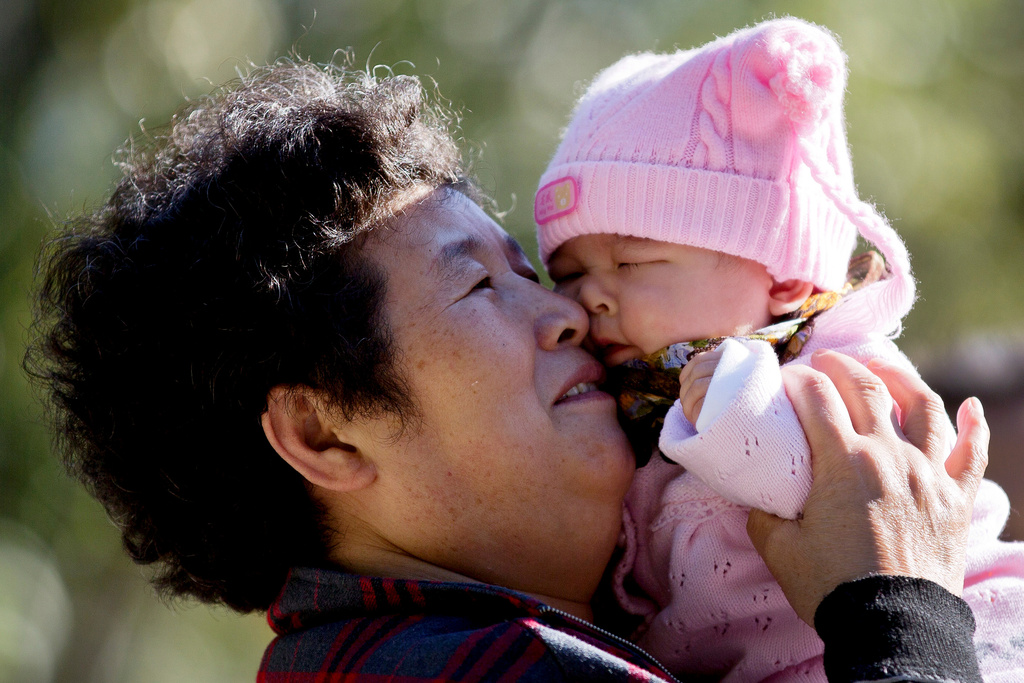 FILE - A Chinese woman plays with her grandchild at the Ritan Park, in Beijing, China on Oct. 31, 2012. (AP Photo/Andy Wong, File)