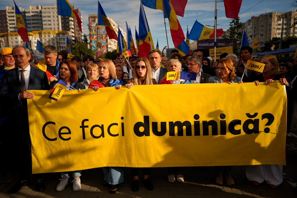 Moldova's Prime Minister Dorin Recean, center, stands behind supporters holding a poster that reads "What are you doing on Sunday?", during a pro-EU rally of the ruling Party of Action and Solidarity (PAS), in Chisinau, Moldova, Friday, Sept. 26, 2025, ahead of parliamentary elections taking place on Sept. 28. (AP Photo/Vadim Ghirda)