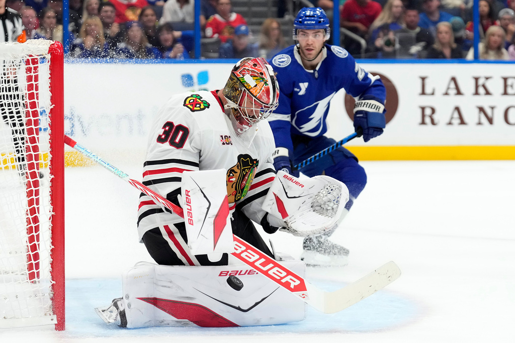 Chicago Blackhawks goaltender Spencer Knight (30) makes a save as Tampa Bay Lightning center Brayden Point (21) moves in for a rebound during the second period of an NHL hockey game Thursday, Oct. 23, 2025, in Tampa, Fla. (AP Photo/Chris O'Meara)