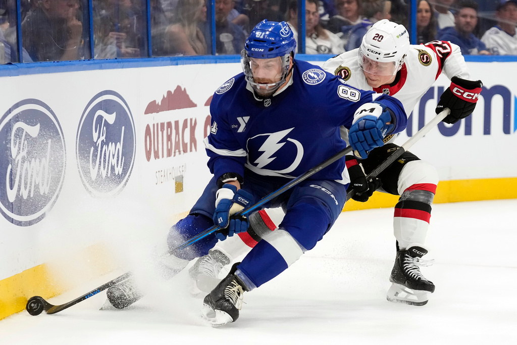 Tampa Bay Lightning defenseman Erik Cernak (81) beats Ottawa Senators left wing Fabian Zetterlund (20) to a loose puck during the third period of an NHL hockey game Thursday, Oct. 9, 2025, in Tampa, Fla. (AP Photo/Chris O'Meara)