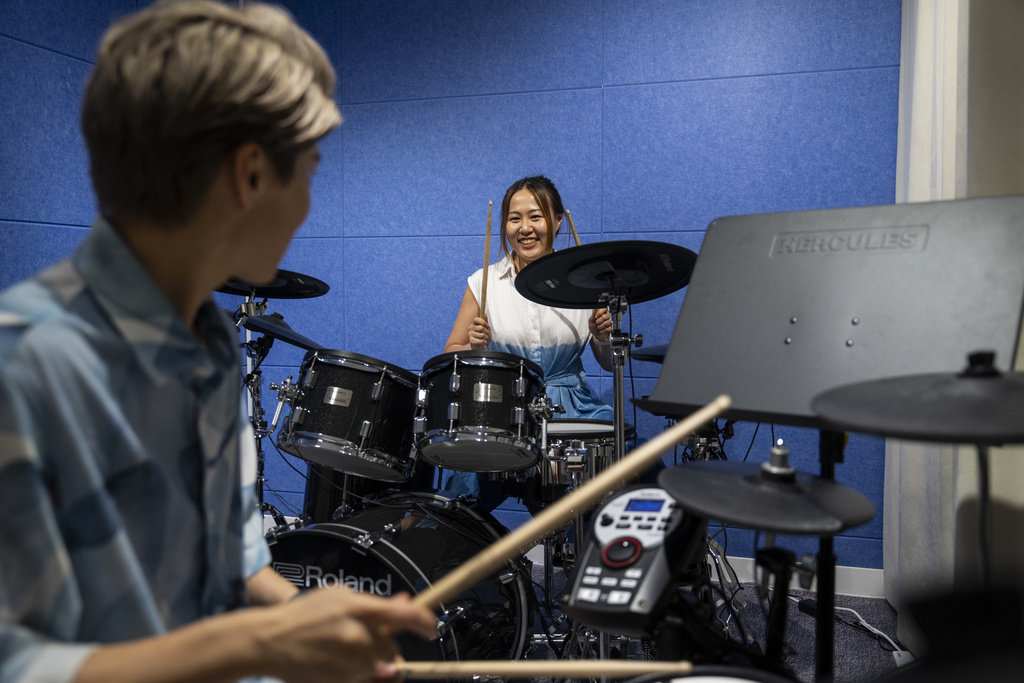 Same-sex partners Jaedyn Yu, left, and Gloria Tsang play drums in a band room in Hong Kong, Sunday, Aug. 24, 2025. (AP Photo/Chan Long Hei)
