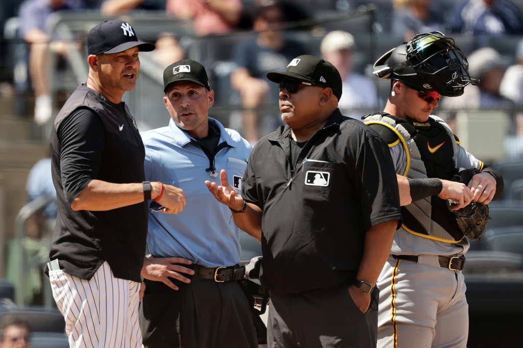New York Yankees manager Aaron Boone, left, argues with umpire Adrian Johnson, second from right, and home plate umpire Quinn Wolcott, second from left, after a pitch-clock violation was charged to Yankees' batter José Caballero in the sixth inning during the first baseball game of a doubleheader against the Pittsburgh Pirates, Wednesday, July 22, 2026, in New York. (AP Photo/Adam Hunger)