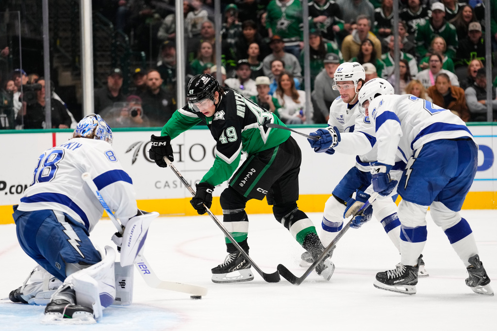 Dallas Stars center Justin Hryckowian (49) takes a shot as Tampa Bay Lightning goaltender Andrei Vasilevskiy, left, Declan Carlile, rear, and Maxwell Crozier (24) defend in the first period of an NHL hockey game in Dallas, Sunday, Jan. 18, 2026. (AP Photo/Tony Gutierrez)
