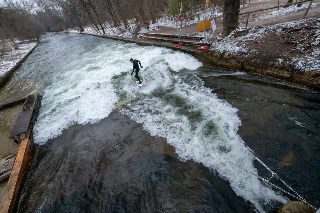 A man tries out the temporary Eisbach wave in the English Garden in Munich, Germany, Friday Dec. 26, 2025. (Peter Kneffel/dpa via AP)