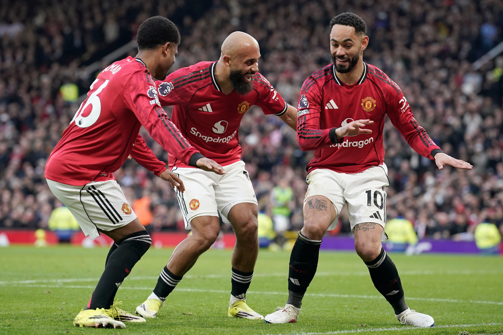 Manchester United's Matheus Cunha, right, celebrates with Manchester United's Amad Diallo, left, and Manchester United's Bryan Mbeumo after scoring his side's second goal during the English Premier League soccer match between Manchester United and Fulham in Manchester, England, Sunday, Feb. 1, 2026. (AP Photo/Dave Thompson)