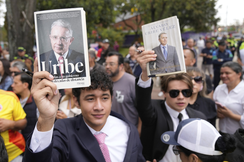 Supporters of former Colombian President Alvaro Uribe displays books during his visit to the site where presidential hopeful and Sen. Miguel Uribe Turbay was fatally shot during a political rally in Bogota, Colombia, Saturday, Aug. 23, 2025. (AP Photo/Fernando Vergara)