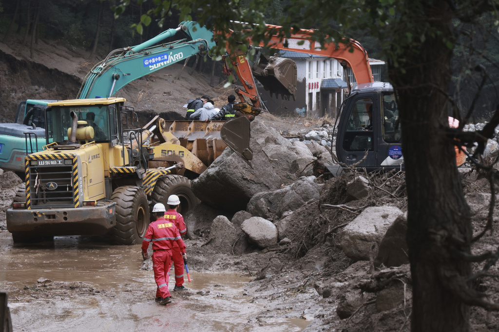 In this photo released by Xinhua News Agency, Rescuers work to restore a road damaged by mountain torrents following a heavy downpour, in Yuzhong County of northwest China's Gansu Province, Friday, Aug. 8, 2025. (Jin Wangui/Xinhua via AP)