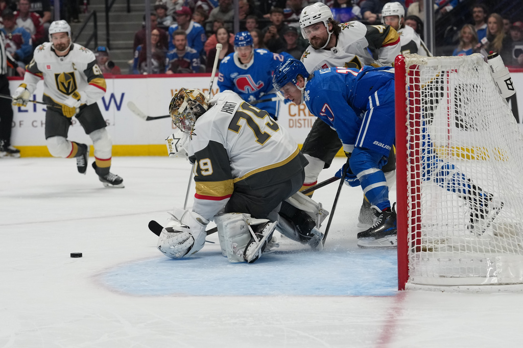 Colorado Avalanche center Parker Kelly, front right, fights past Vegas Golden Knights defenseman Rasmus Andersson, back right, as goaltender Carter Hart stops a shot in the first period of an NHL hockey game Saturday, April 11, 2026, in Denver. (AP Photo/David Zalubowski)