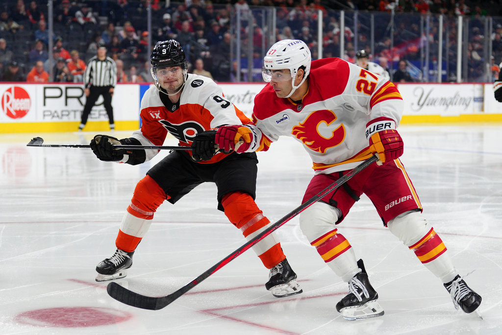 Calgary Flames' Matt Coronato (27) and Philadelphia Flyers' Jamie Drysdale (9) race for the puck during the third period of an NHL hockey game, Sunday, Nov. 2, 2025, in Philadelphia. (AP Photo/Derik Hamilton)