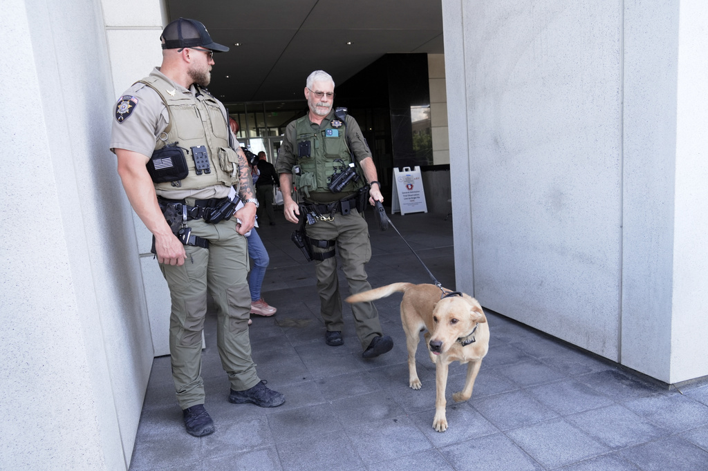 Police officials handle a dog as people access the limited public seating available at a preliminary hearing for Tyler Robinson, the Utah man accused of fatally shooting Charlie Kirk, in Provo, Utah, Wednesday, July 8, 2026. (AP Photo/Ty ONeil)