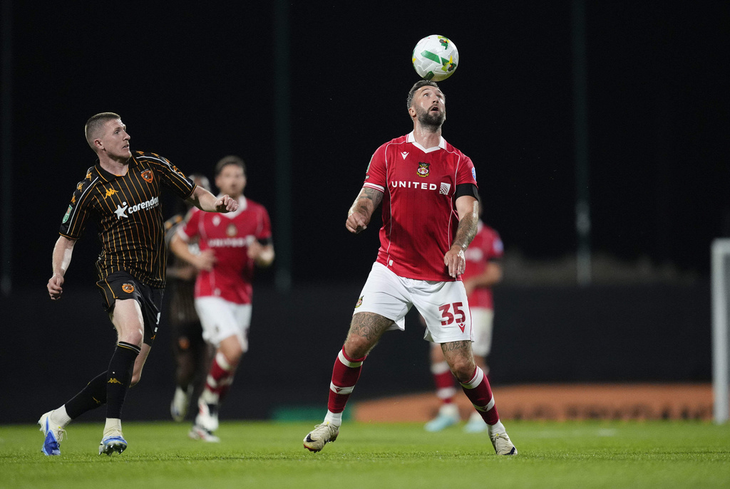 Hull City's John Lundstram, left, and Wrexham's Ollie Palmer battle for the ball during the English League Cup first round soccer match between Wrexham and Hull City at SToK Racecourse, Wrexham, Wales, Tuesday Aug. 12, 2025. (Nick Potts/PA via AP)