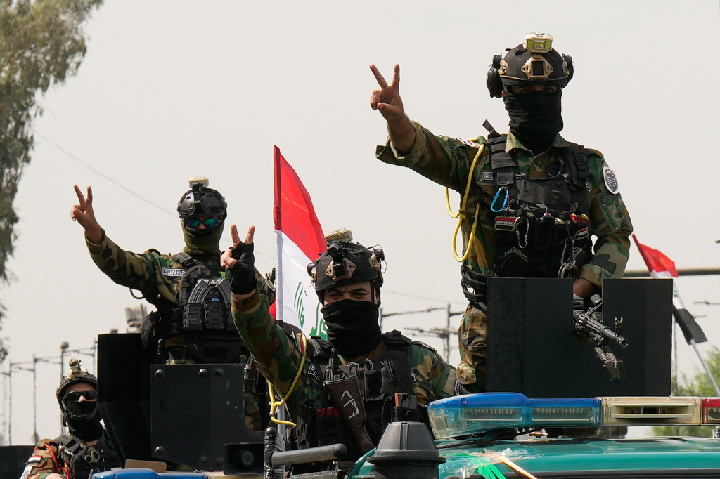 Iraqi security officers flash victory signs while riding in vehicles decorated with national flags during a convoy celebrating the complete withdrawal of U.S. troops from Iraq, in Baghdad, Iraq, Wednesday, Sept. 30, 2026. (AP Photo/Hadi Mizban)