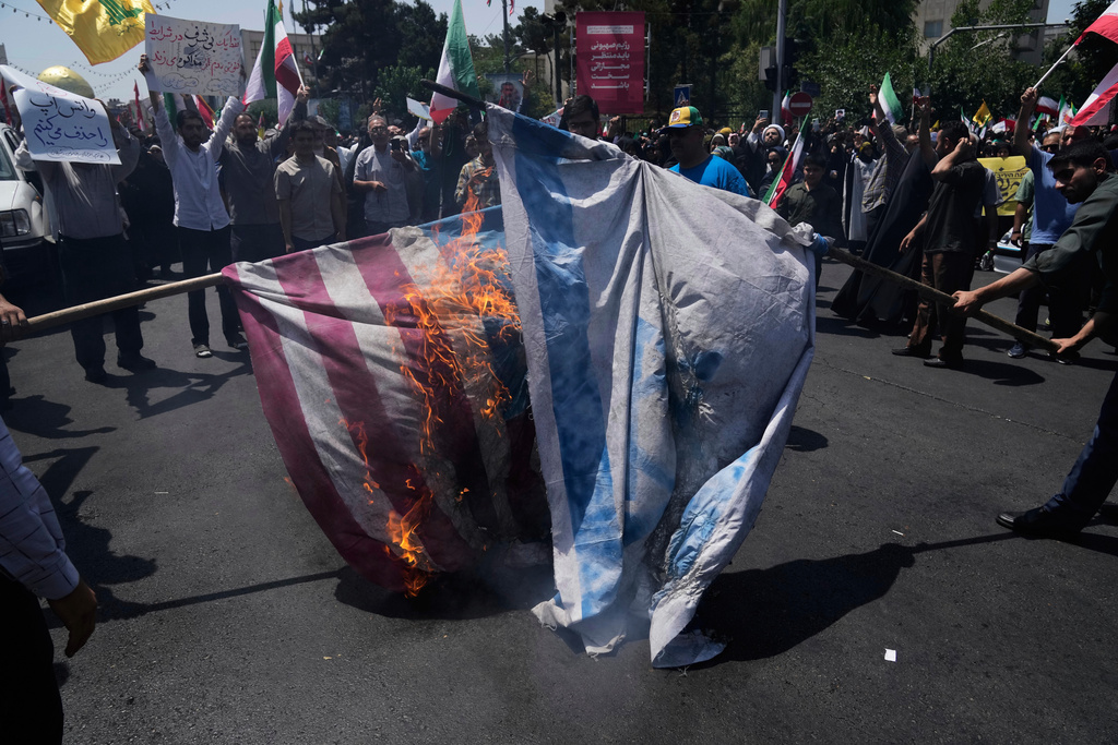 FILE - Iranian protestors burn representations of the Israeli and U.S. flags during a protest to condemn Israeli attacks on multiple cities across Iran, after the Friday prayers ceremony in Tehran, Iran, Friday, June 20, 2025. (AP Photo/Vahid Salemi), File)