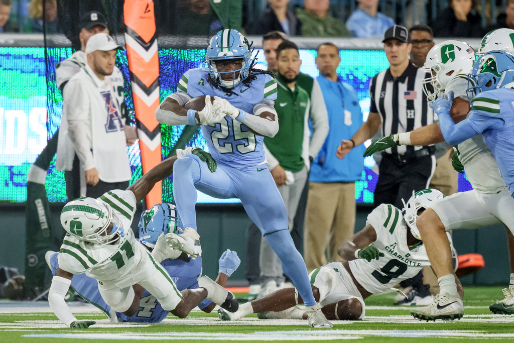 Tulane running back Jamauri McClure (25) runs against Charlotte defensive back Dwight Bootle II (11) during the second half of an NCAA college football game in New Orleans, Saturday, Nov. 29, 2025. (AP Photo/Matthew Hinton)