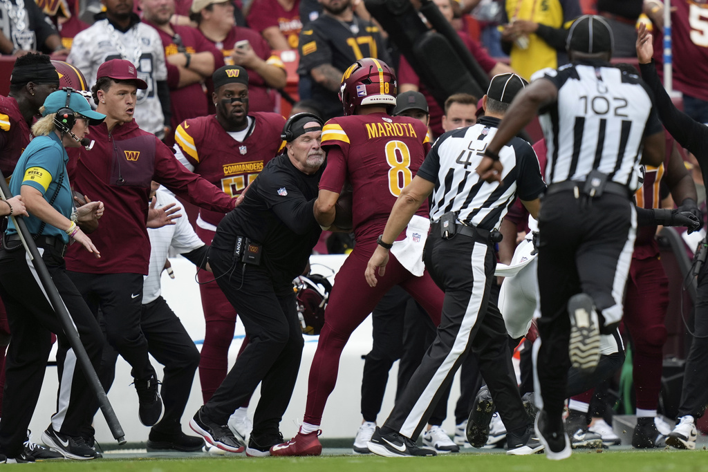 Washington Commanders Dan Quinn is run into on the sideline during the first half of NFL football game against the Las Vegas Raiders, Sunday, Sept. 21, 2025, in Landover, Md. (AP Photo/Stephanie Scarbrough)