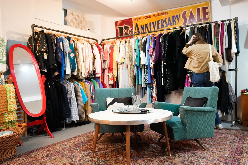A shopper looks at a rack at Mothership, a vintage and thrift store, Thursday, March 26, 2026, in New York. (AP Photo/Alyssa Goodman)